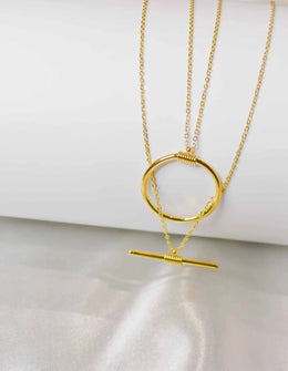 layered bar and circle pendant necklace on white silk background