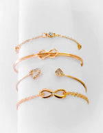 Infinity charm bracelet in gold paired with heart ring and chain
