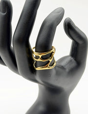 Gold ring on a black mannequin hand against a white background