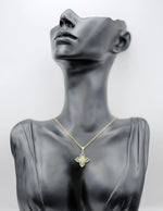 Mannequin wearing a gold necklace with a butterfly pendant on a gray background