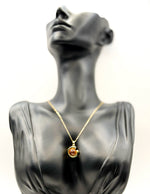 Waterproof gold celestial necklace with amber stone on white silk.