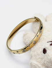 Hypoallergenic non-tarnish high polish gold domed bangle with cubic zirconia.