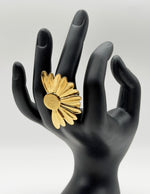 Waterproof gold sunburst flower ring on wooden display Dubai.