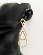 Gold teardrop earring on a black mannequin ear with a white background