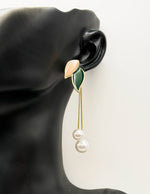 Earring with leaf and pearl design on a black background