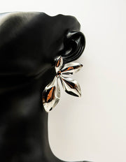 Close up of imitation jewelry uae statement studs featuring high-shine molten metal texture.