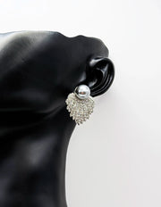 Silver earring with a pearl on a black mannequin ear against a white background