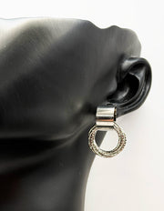 Silver earring on a black ear model with a white background